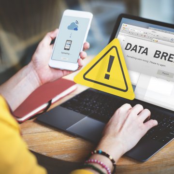 identity guard id theft protection service best woman in yellow blouse on laptop with phone in hand warning data breach on display 